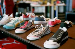 A variety of casual sneakers in different colors and styles are displayed on a table in a store.