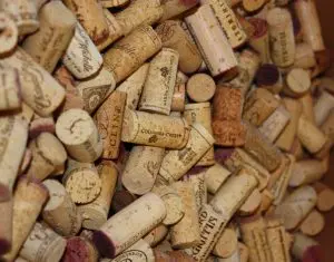 A large pile of assorted wine corks, some stained with wine, displaying various winery names and logos.