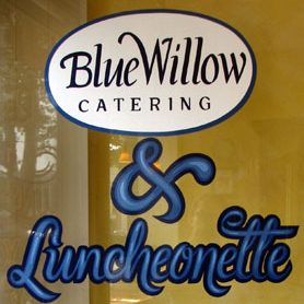 Sign with "Blue Willow Catering & Luncheonette" in stylized blue and white lettering on a window.